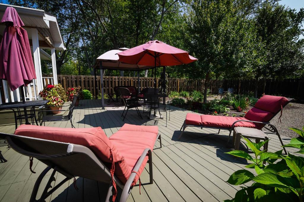 a deck with chairs and an umbrella and a table at The Lakehouse Inn Geneva in Geneva-on-the-Lake