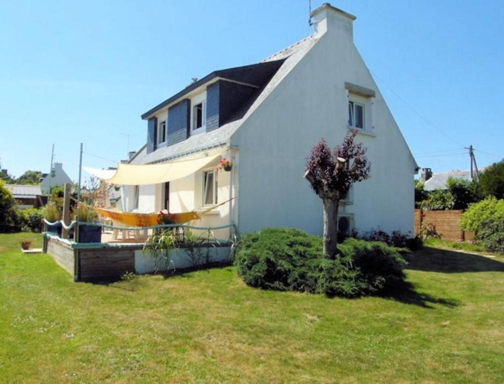 une petite maison blanche avec un arbre dans la cour dans l'établissement Chambres d'hôtes de Pont C'Hoat, à Névez