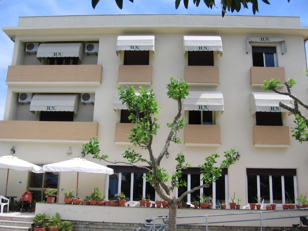 un grand bâtiment blanc avec des parasols en face de celui-ci dans l'établissement Hotel Naviglio, à Marina di Pietrasanta
