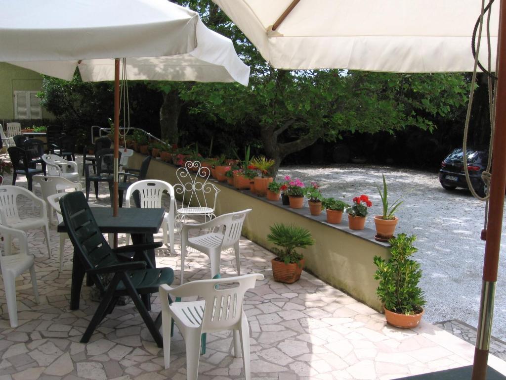 a patio with white chairs and tables and an umbrella at Hotel Naviglio in Marina di Pietrasanta
