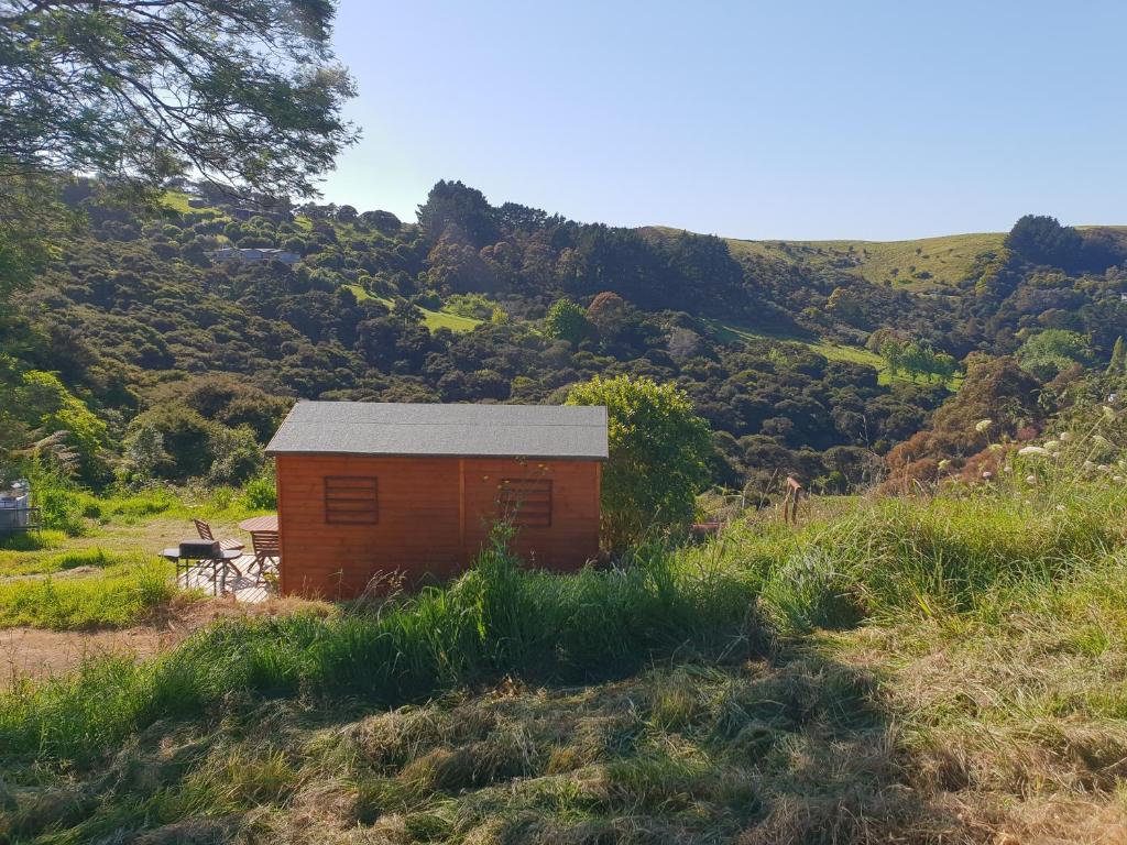 a small building in a field with a mountain at Wild Days Accommodation in Palm Beach