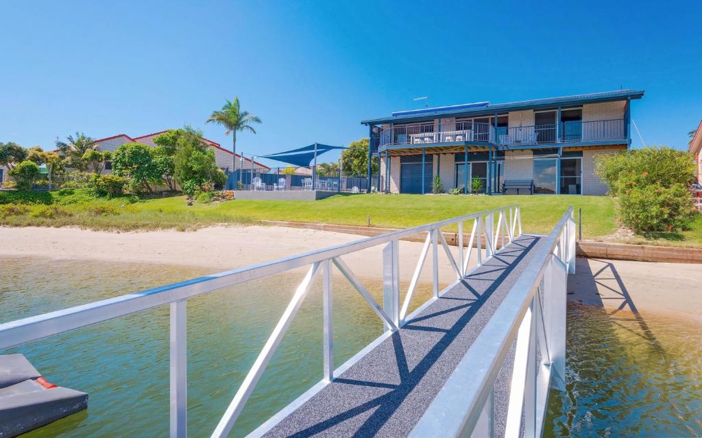 a house on the beach with a bridge over the water at Pandanus - LJHooker Yamba in Yamba