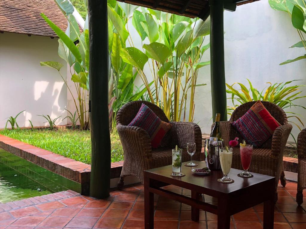 eine Terrasse mit Stühlen und einem Tisch mit Gläsern darauf in der Unterkunft Maison Houng Chanh - Luang prabang in Luang Prabang