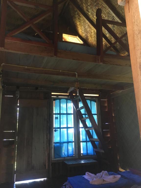 an attic room with a ladder and a window at Eka's Bungalows in Maninjau