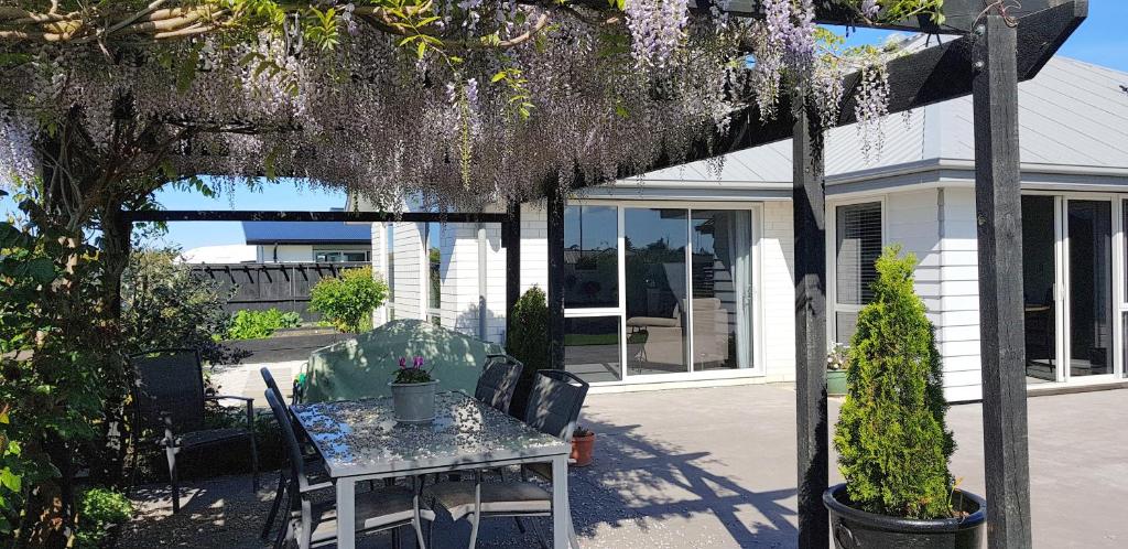 a pergola with a table and chairs on a patio at Courtenay B & B in Kaiapoi