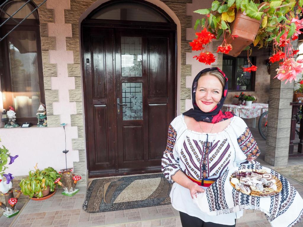 une femme tenant une plaque de nourriture devant une porte dans l'établissement Vama Casă de vacanţă La marinaru' ratacit, à Vama