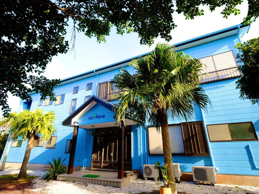 a blue building with palm trees in front of it at Kokumin Shukusha Sun Marina in Kaminato