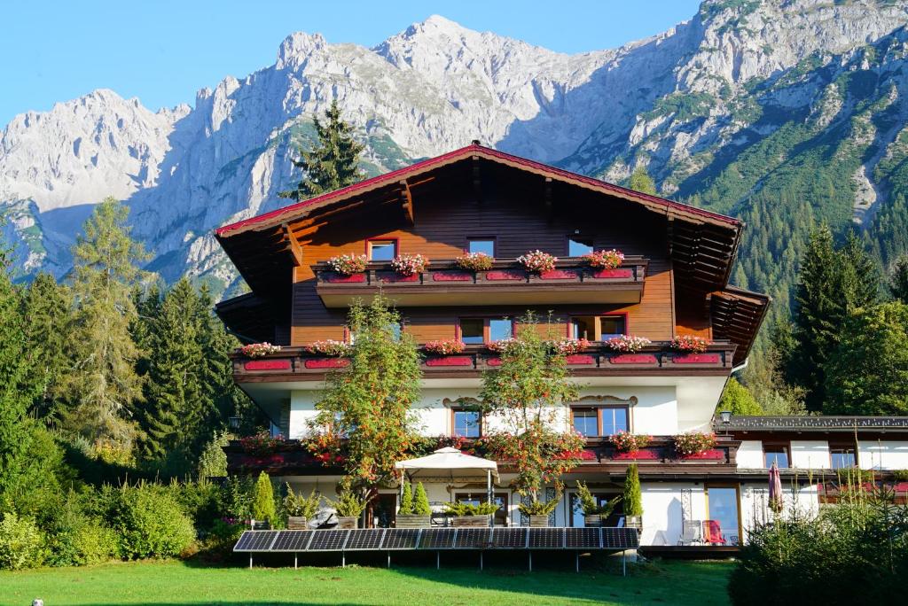 une maison dans les montagnes avec des montagnes en arrière-plan dans l'établissement Pension Dachsteinhof, à Ramsau am Dachstein