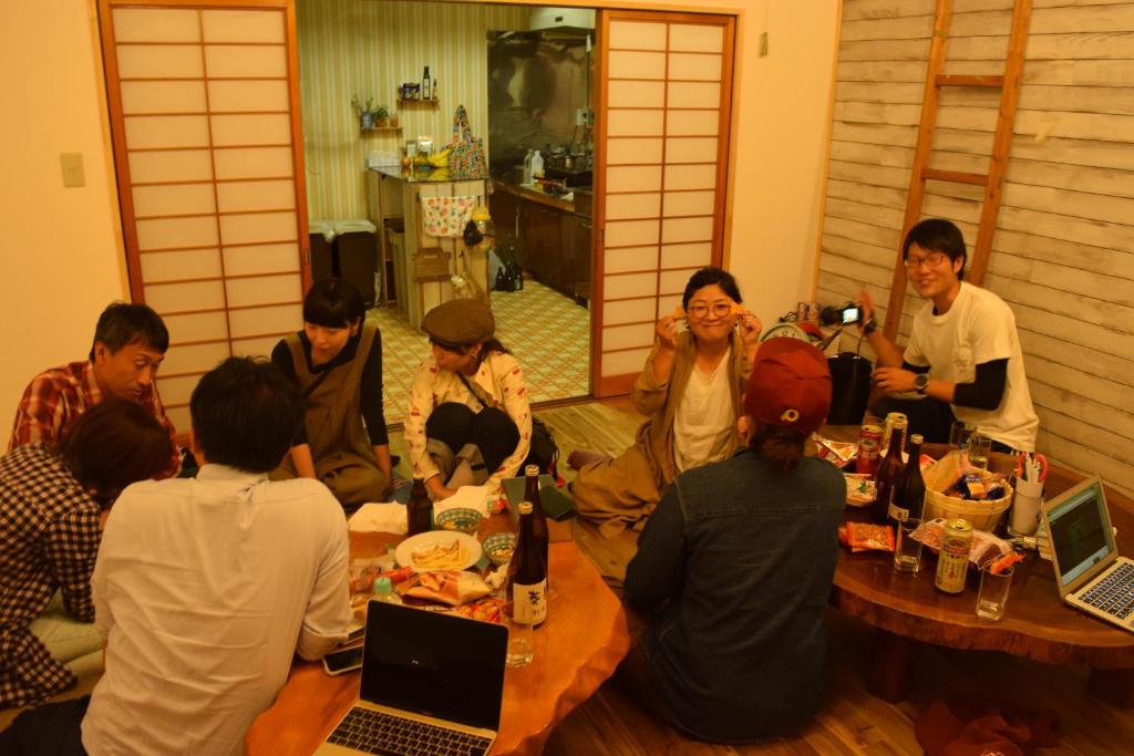 a group of people sitting around a table with laptops at Guest House Minato in Miyako