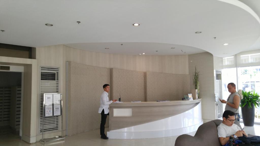a man standing at a counter in a lobby at Cozy 1BR-Grace Residences in Manila