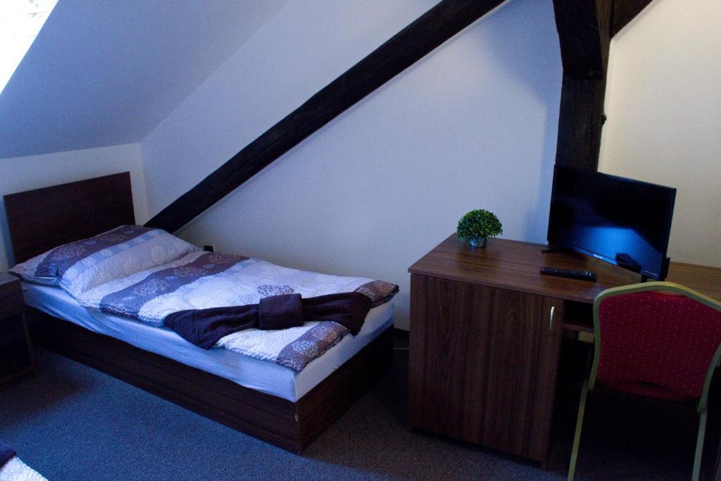 a bedroom with a bed and a desk with a computer at Hotel Zlatý Anděl in Žatec