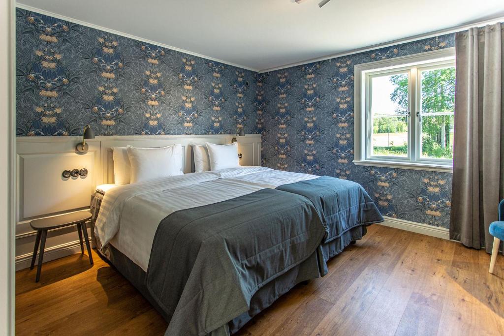 una camera da letto con un letto e carta da parati floreale blu di Lindesbergs Hotell a Lindesberg