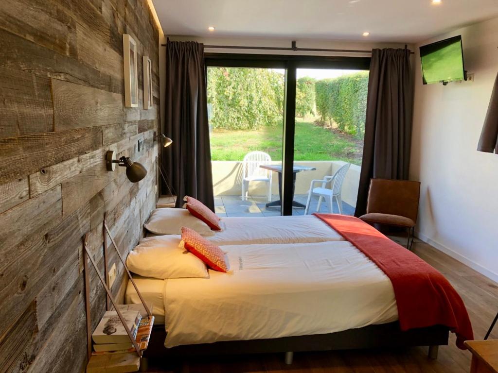 a hotel room with a bed and a view of a patio at Rikkeshoeve vakantiewoning in Sint-Truiden