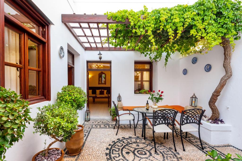 a patio with a table and chairs and a tree at Villa Amalia in Lindos