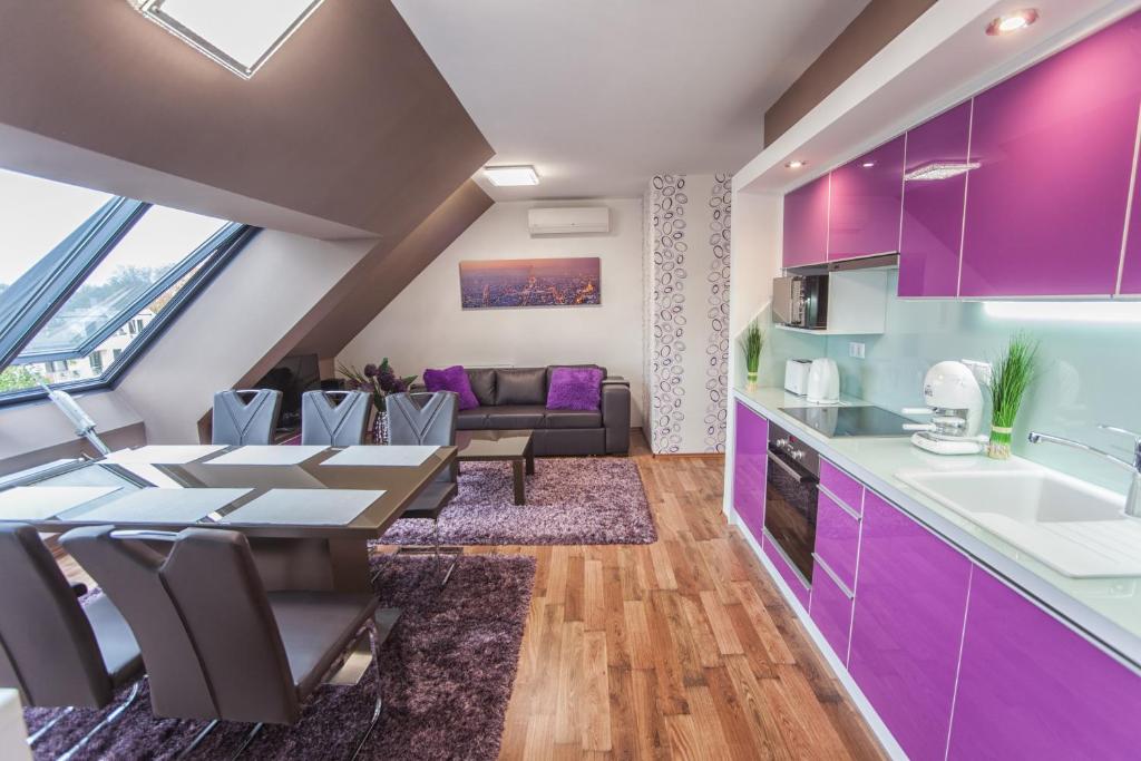 eine Küche und ein Wohnzimmer mit lilafarbenen Schränken und einem Tisch in der Unterkunft Rubin Relax Apartman in Sárvár