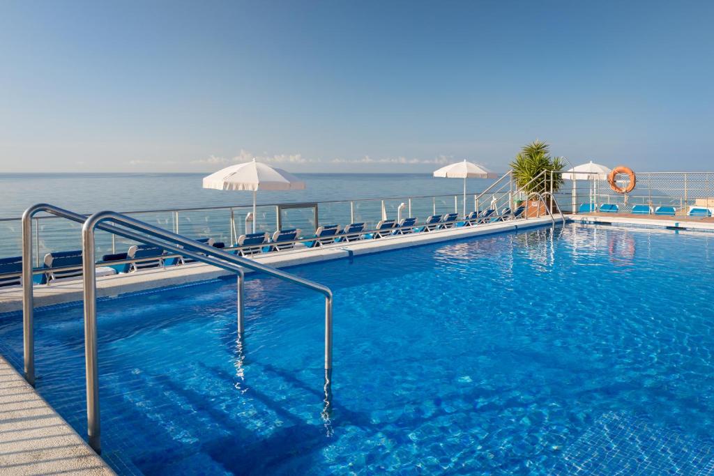 - une grande piscine avec vue sur l'eau dans l'établissement htop Pineda Palace #htopBliss, à Pineda de Mar