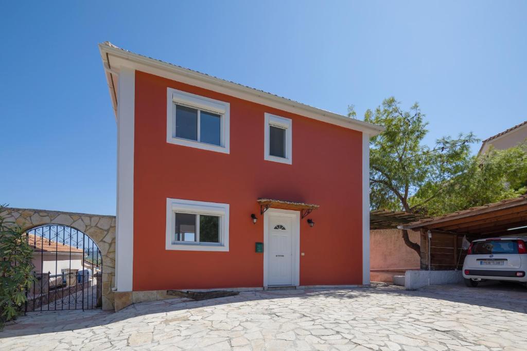 een rood huis met een witte deur op een oprit bij Kali Tychi in Katastárion