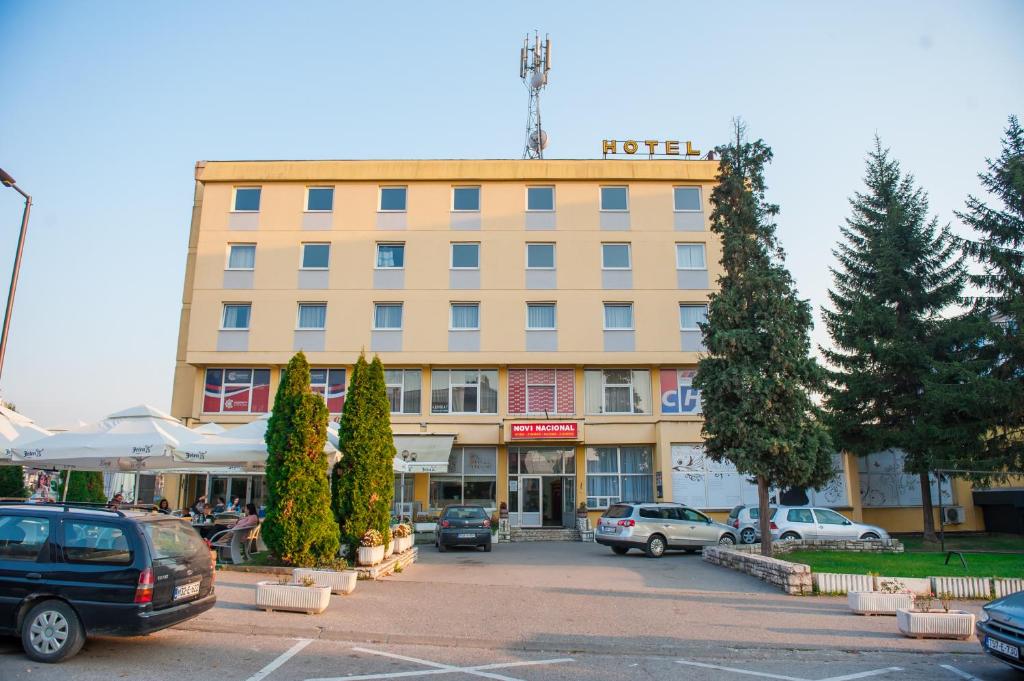 a large building with cars parked in a parking lot at Prenoćište "NACIONAL" in Prnjavor