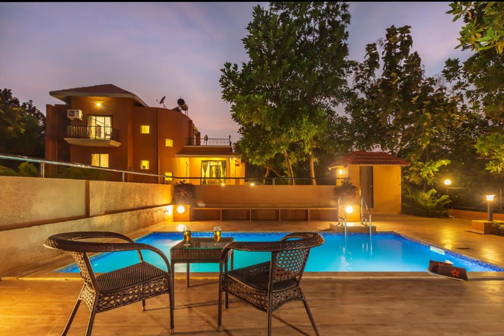un patio con tavolo e sedie accanto alla piscina di SaffronStays Ekaant, Vikramgad - party-perfect pool villa with spacious lawn a Pālghar