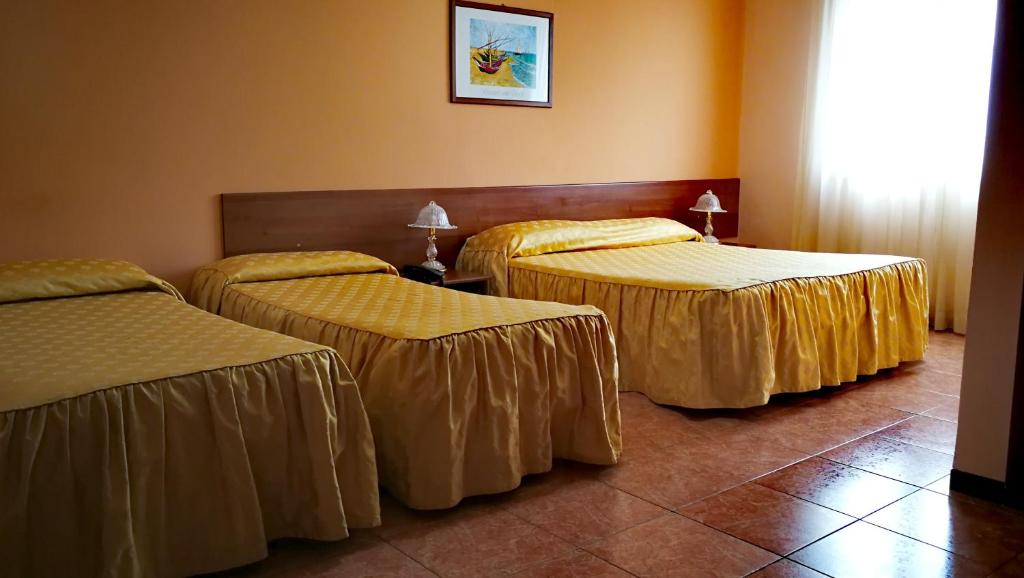 three beds in a hotel room with gold sheets at Valle Degli Ulivi in Motta SantʼAnastasia