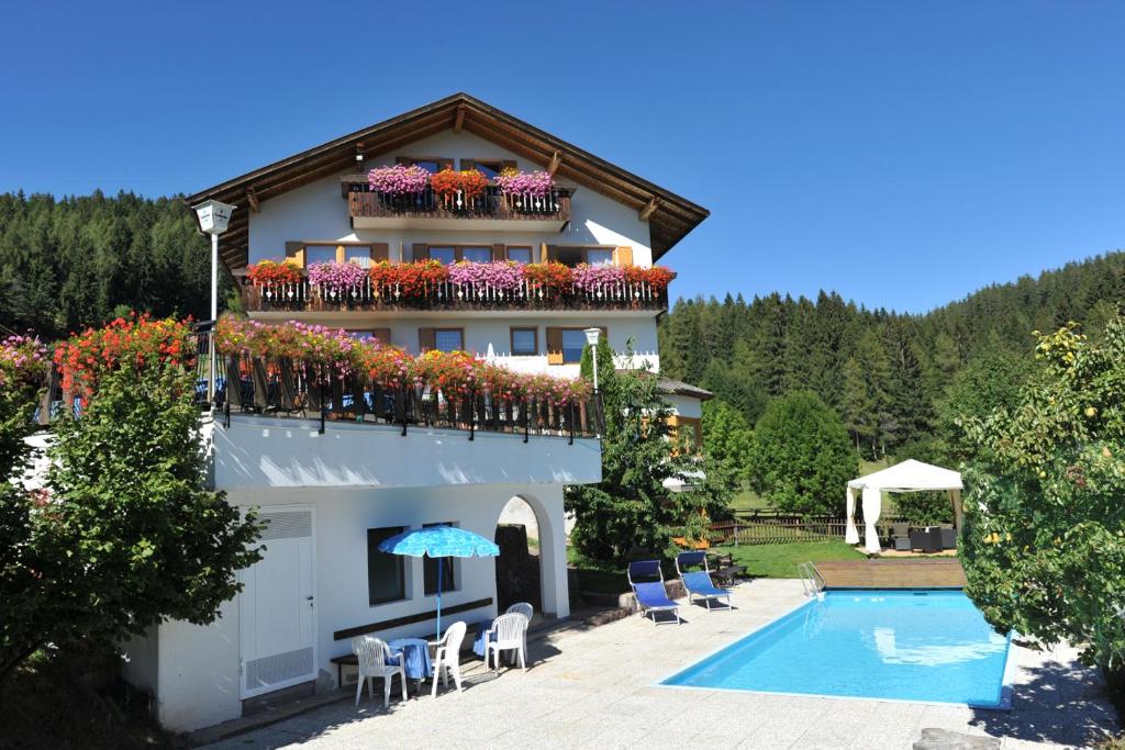 a building with a balcony with flowers and a swimming pool at Hotel Langeshof in Anterivo