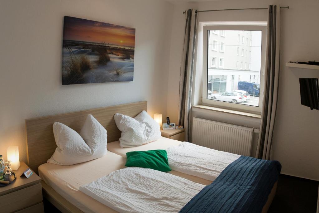 Schlafzimmer mit einem Bett mit weißer Bettwäsche und einem Fenster in der Unterkunft Hotel & Apartment Am Theaterplatz in Bremerhaven