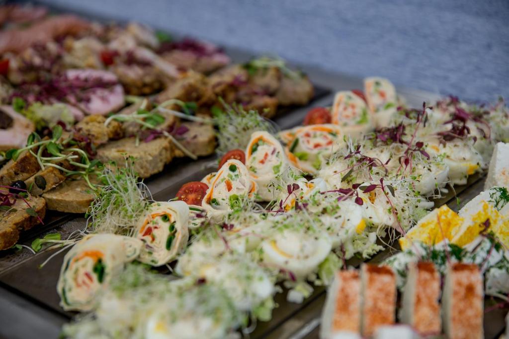 Plated canapés and pinwheel wraps topped with microgreens and sliced eggs on serving trays.