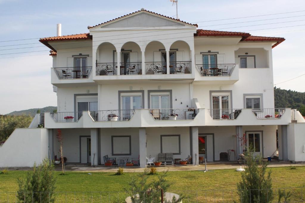 a large white house with windows and balconies at ZEPHYROS ROOMS in Ormos Panagias