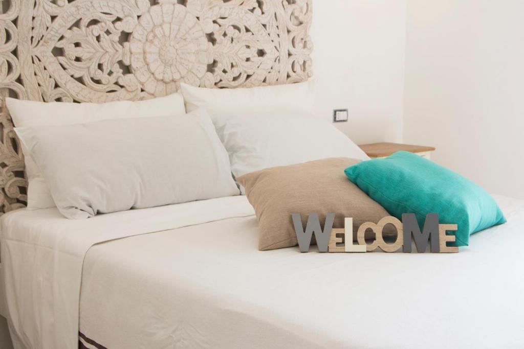 Una cama blanca con almohadas blancas y un cartel de bienvenida. en Filì, en Nápoles