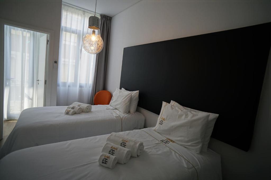 two beds in a hotel room with towels on them at Stylish house - air cond, breakfast, free parking in Vila Nova de Gaia