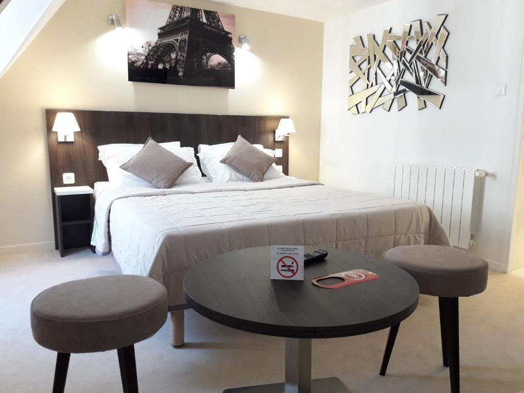 a bedroom with a bed with two stools and a table at Hôtel Mazagran in Paris