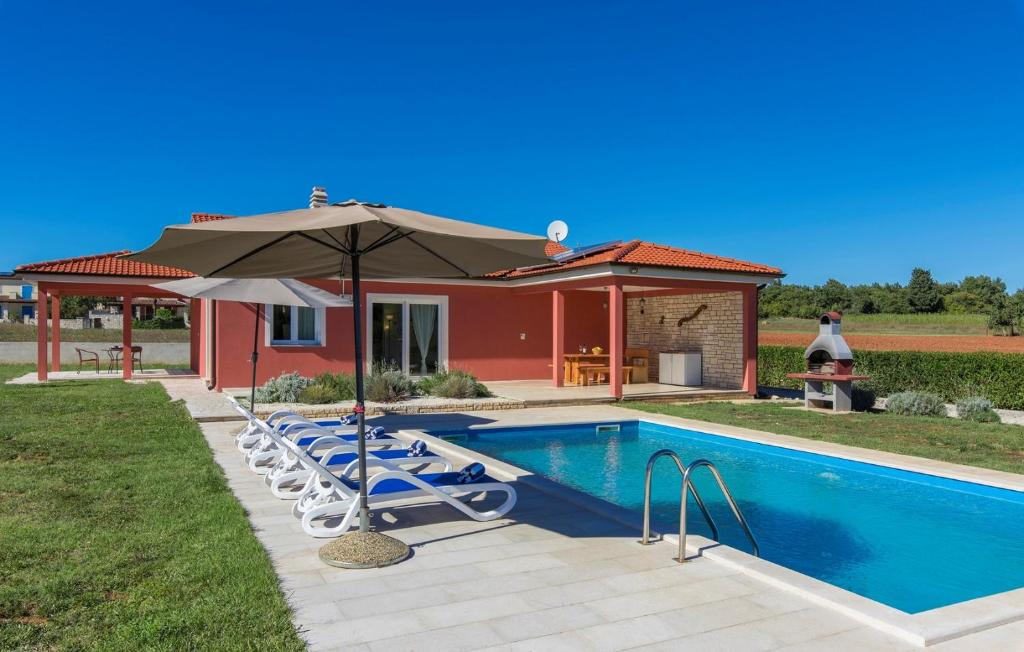 a pool with chairs and an umbrella next to a house at Villa Kata in Rebići