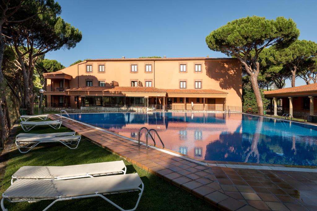 a swimming pool with two lounge chairs in front of a building at Parador de Tordesillas in Tordesillas