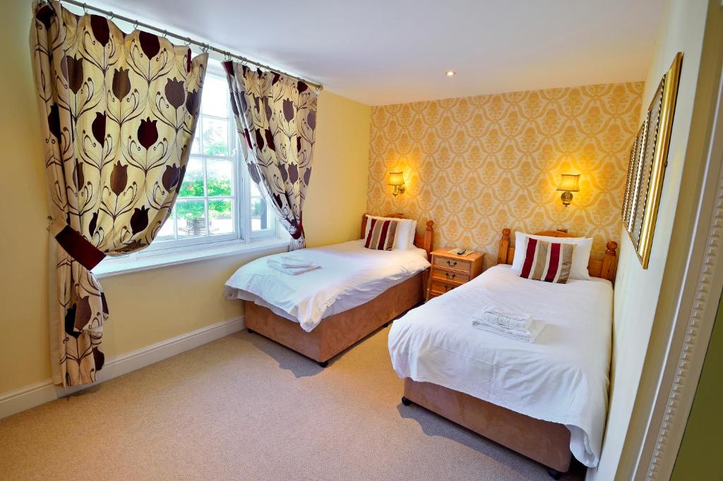 a small bedroom with two beds and a window at The Crown Hotel in Hailsham