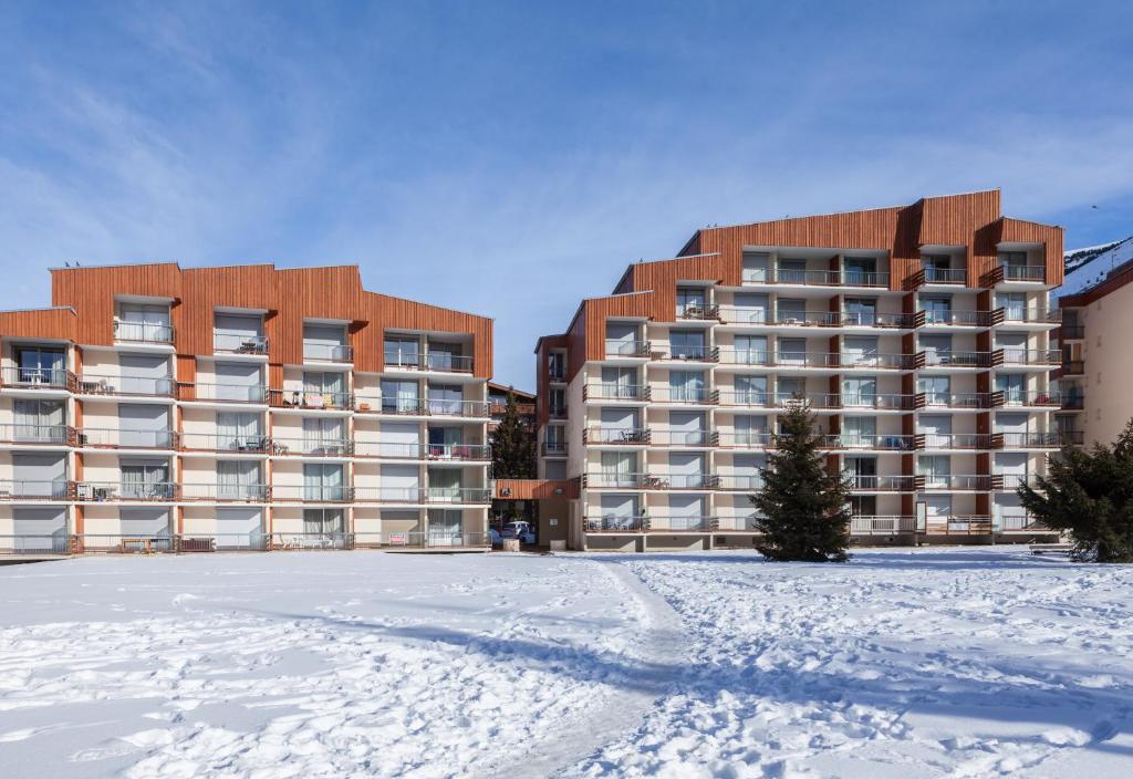 un aparcamiento cubierto de nieve frente a un edificio en Vacancéole - Résidence Côte Brune, en Les Deux Alpes
