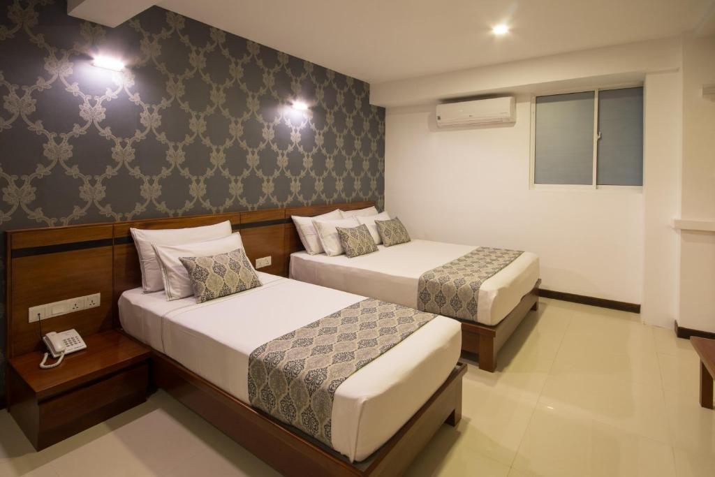 a hotel room with two beds and two lamps at Ceyloni City Hotel in Kandy
