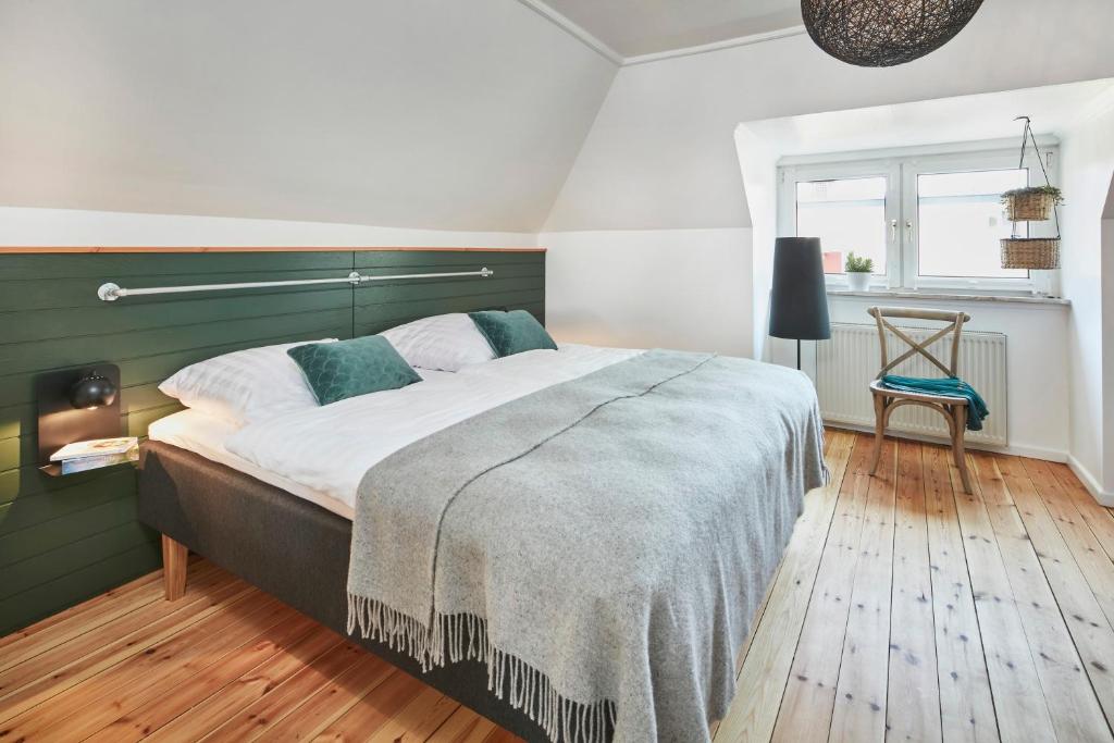 a bedroom with a large bed with a green headboard at Glücksferien- Gänseblümchen in Glücksburg