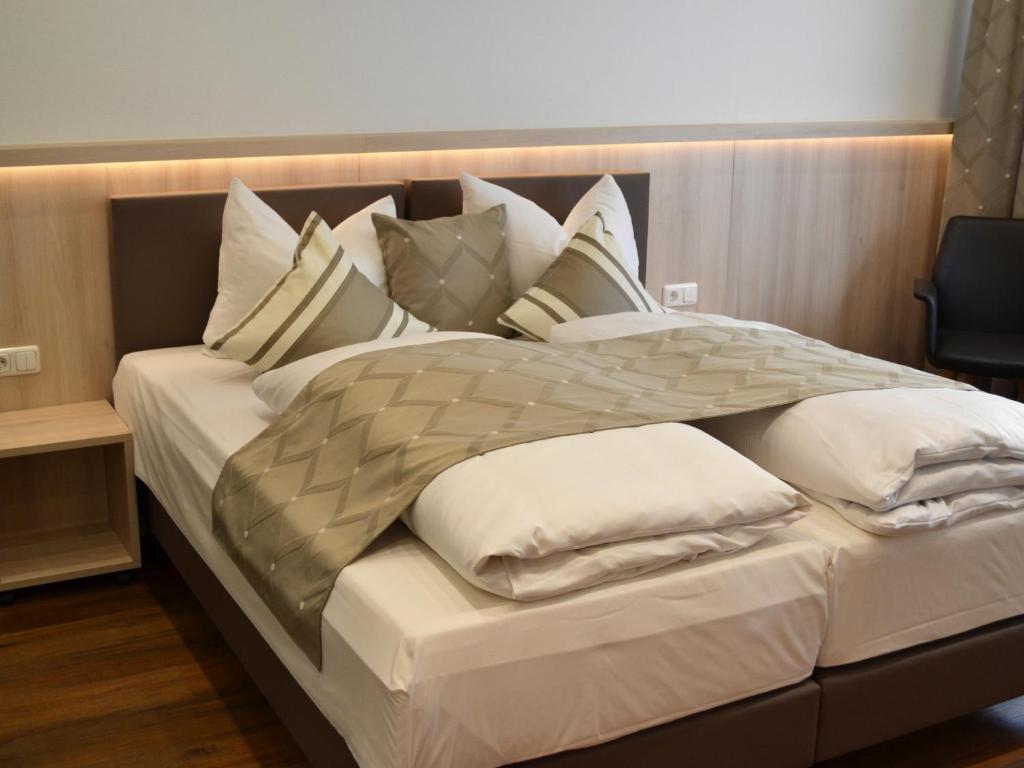 a large bed with white pillows on it at Hotel-Gasthof Weisses Ross in Schwaig bei Nürnberg