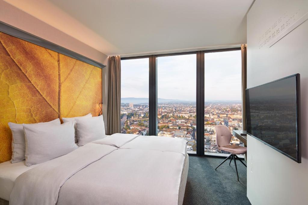 a hotel room with a large bed and large windows at Hyperion Hotel Basel in Basel