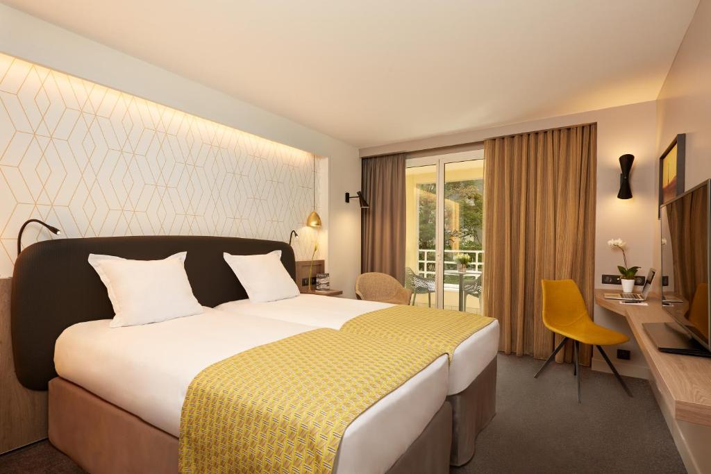 a hotel room with a bed and a desk and a television at Auteuil Tour Eiffel in Paris