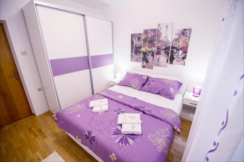 - une chambre avec un lit violet et 2 serviettes dans l'établissement Apartman Katarina, à Trebinje