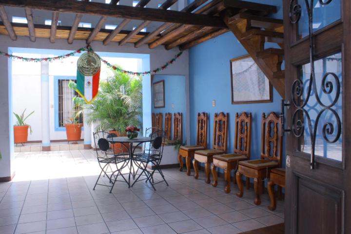 une salle à manger avec une table, des chaises et un mur bleu dans l'établissement HOTEL NIUT-JA, à Oaxaca
