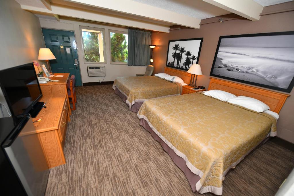 Costa Mesa Inn - Newport Beach Area في كوستا ميسا: غرفة فندقية بسريرين وتلفزيون بشاشة مسطحة