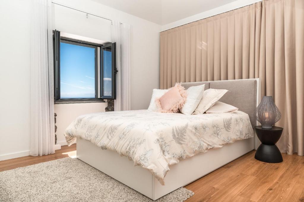 een witte slaapkamer met een bed en een raam bij BHF Residences Ying Yang in Calheta