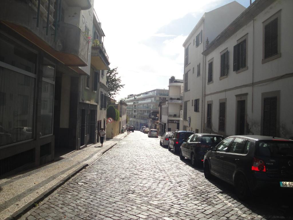 una calle adoquinada con coches aparcados en una ciudad en Violeta House en Funchal