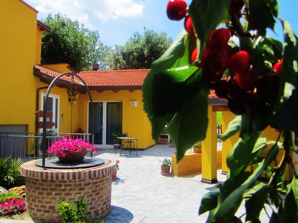 una casa gialla con una fontana di fronte a un cortile di Osteria da Cesare e Locanda a Castel San Pietro Terme