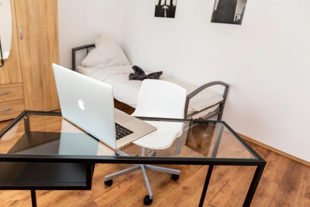 ブレーマーハーフェンにあるAVR Apartment HOF 7のガラステーブル、椅子にノートパソコンを用意しています。