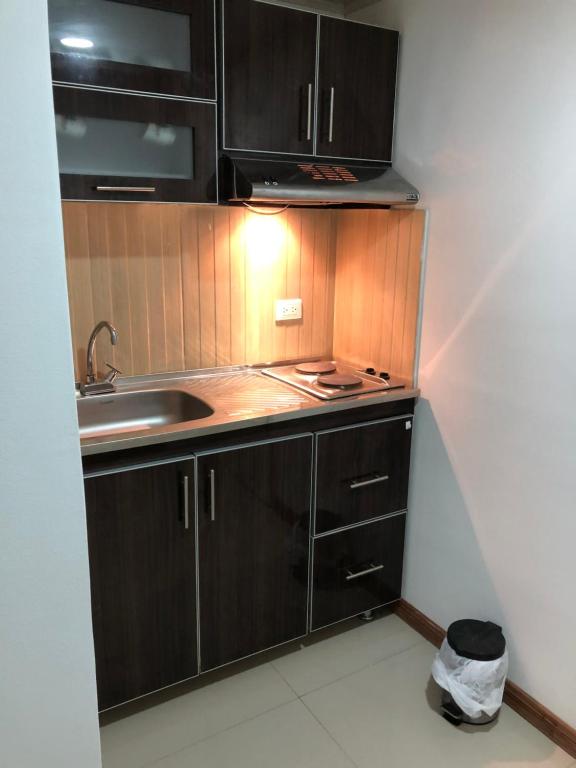 una pequeña cocina con armarios de madera y fregadero en Apt nororiente 203, en Bogotá