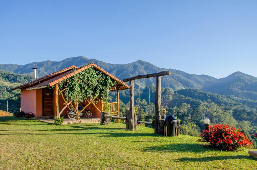 a cabin in a field with mountains in the background at Pousada Barra Das Antas in Visconde De Maua