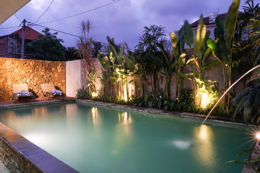 a swimming pool with lights in a backyard at night at Narda House Ubud in Ubud